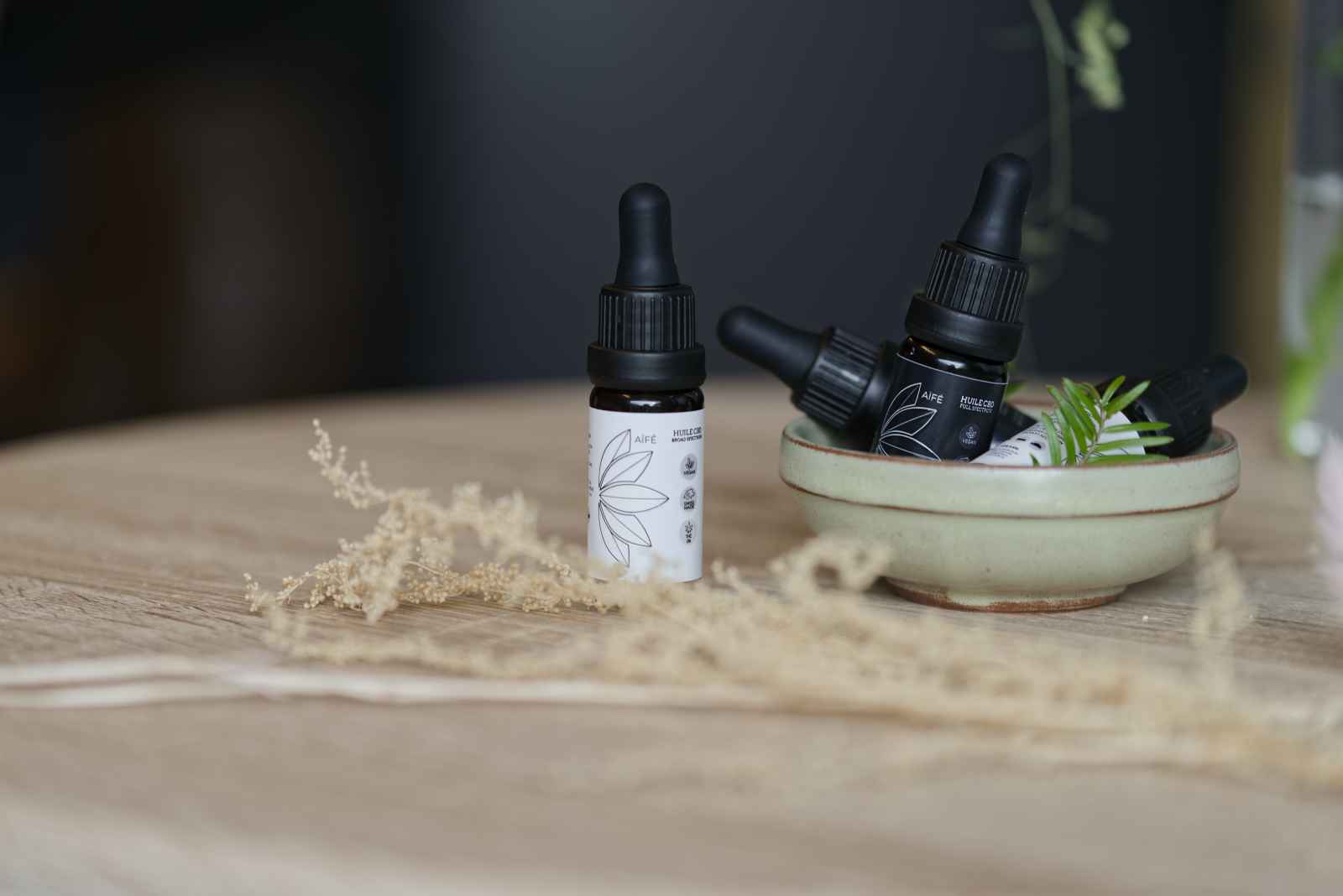 Huiles de CBD aïfé poses sur une table en bois.