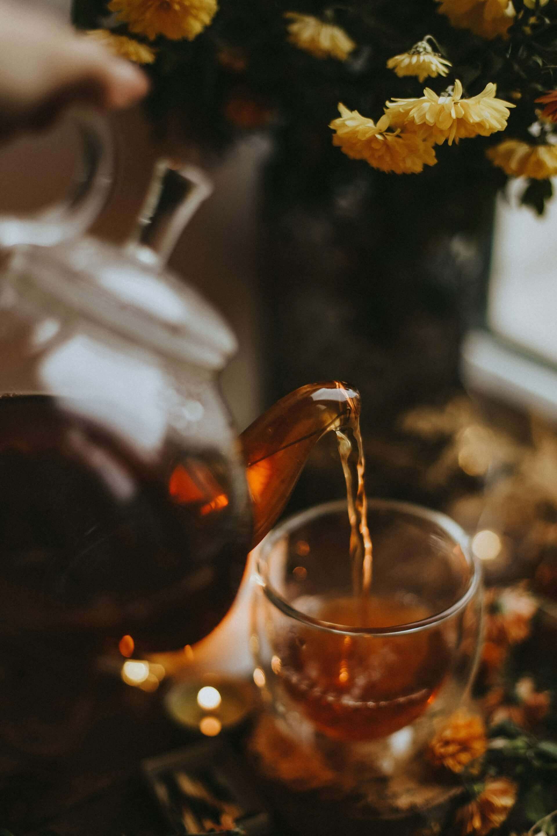 Théière versant une infusion au CBD dans une tasse.